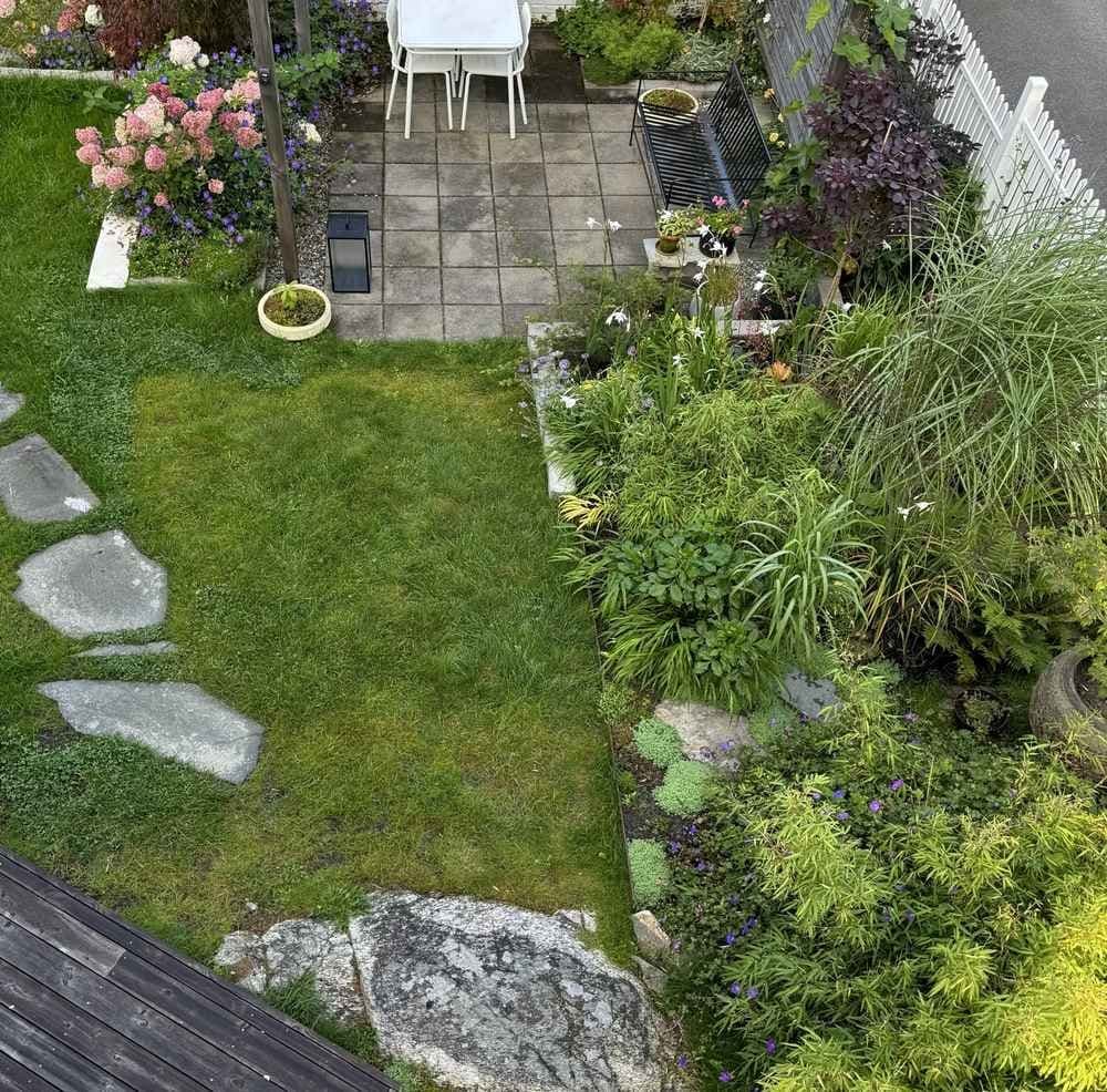 Oversiktsbilde av en frodig hage med uteplass. Foto. 