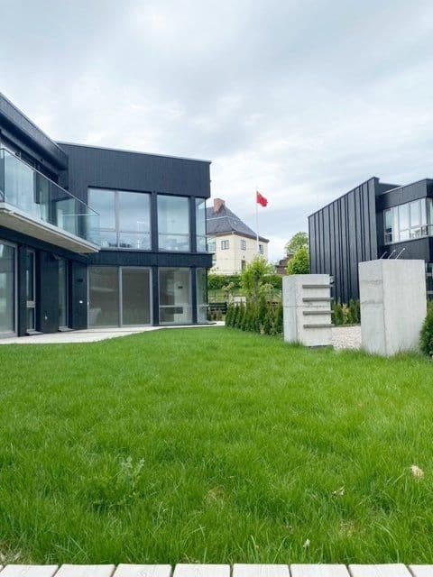 Grønn plen med hus i bakgrunnen. Foto.