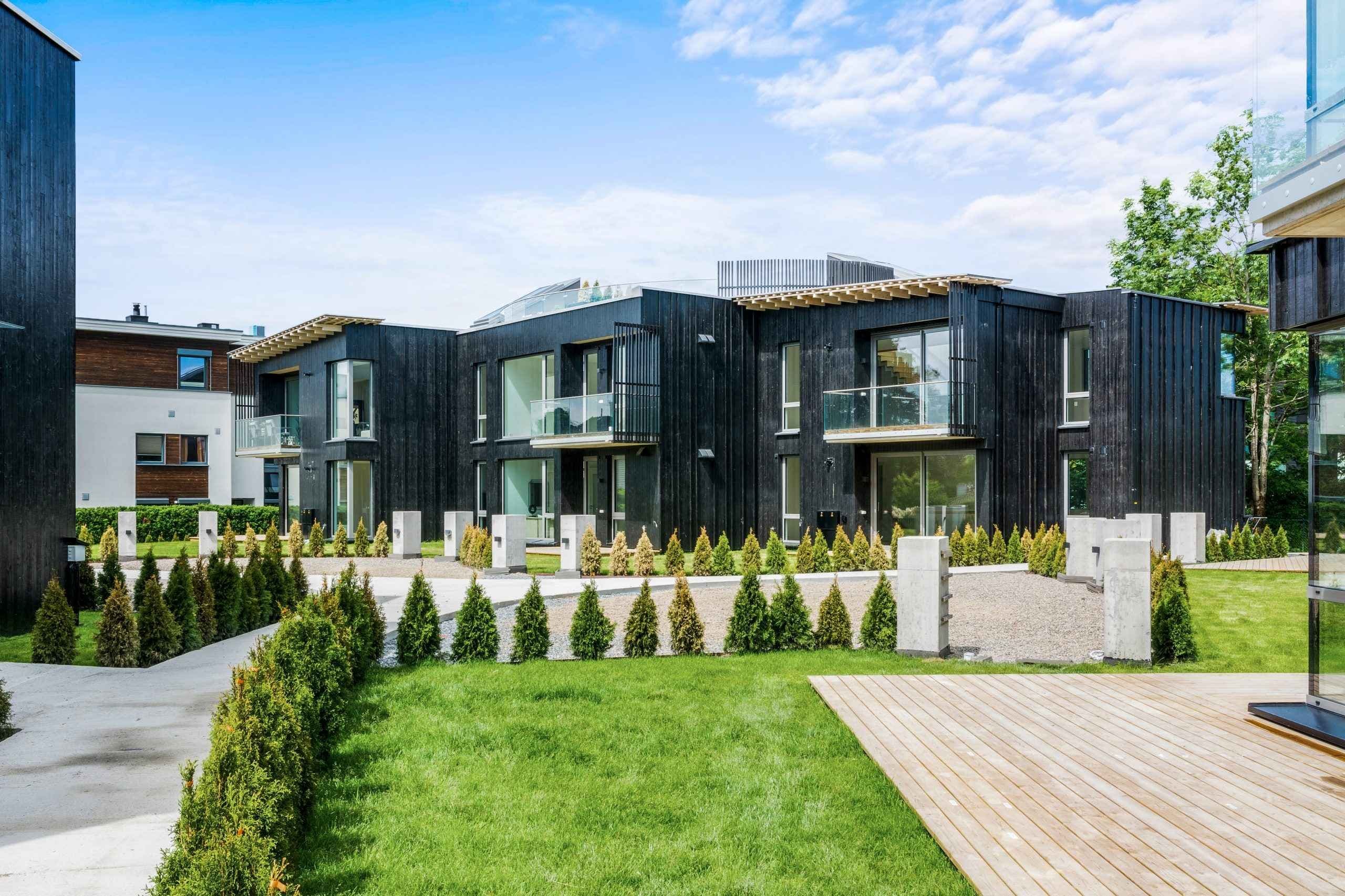 Grønn plen foran moderne leiligheter i sort. Foto.