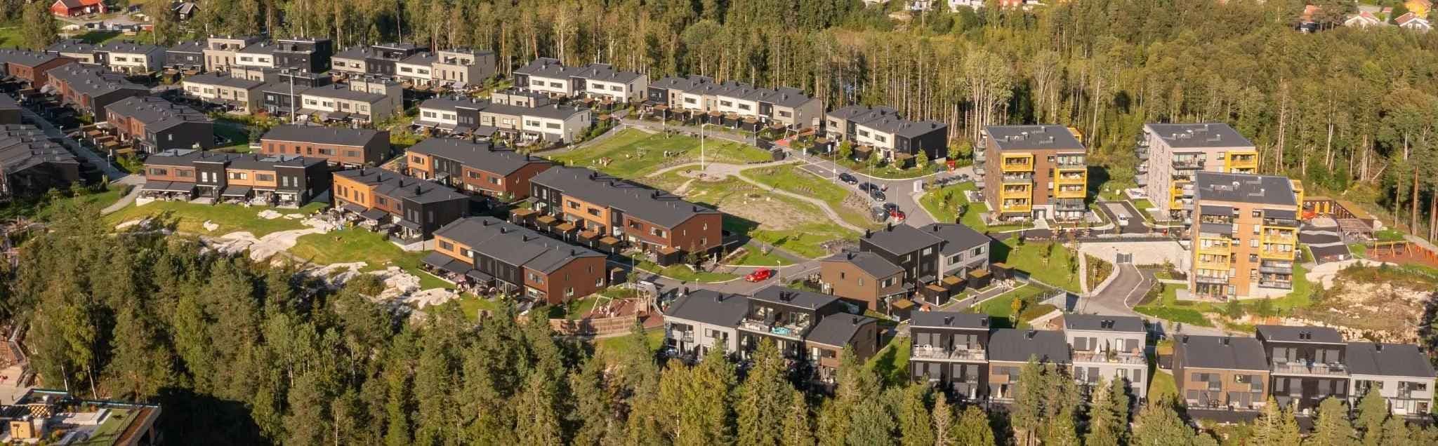 Boligfelt sett fra lufta med grøntområder og skog rundt. Foto.