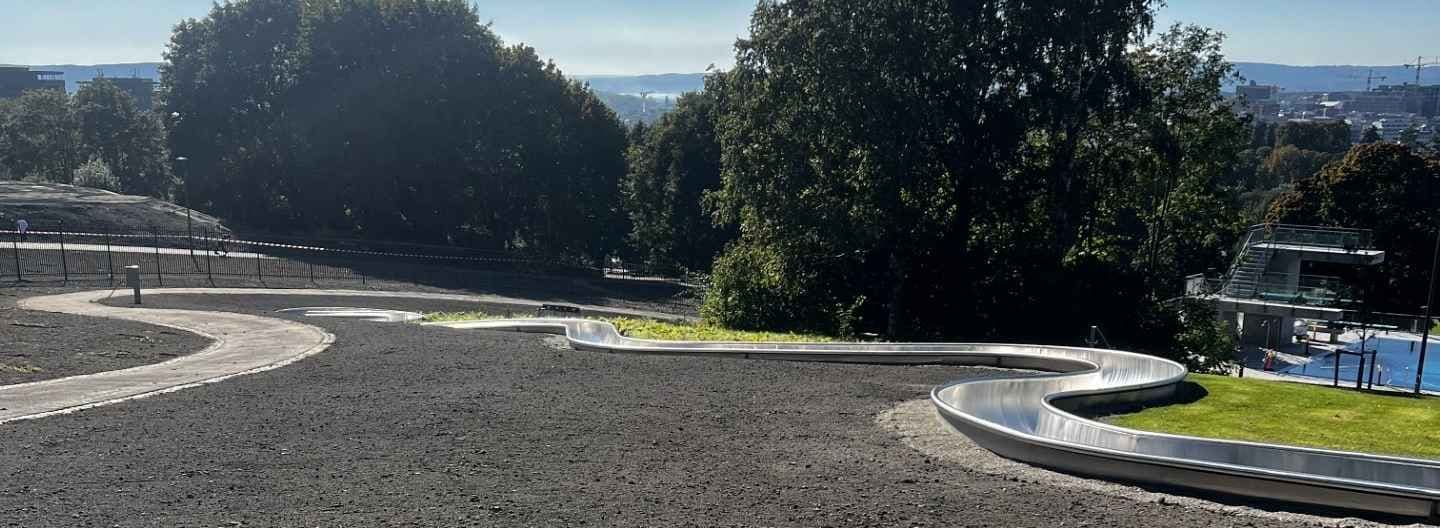 Utsikt over området ved nye Tøyenbadet, med en sklie som bukter seg gjennom det åpne terrenget.